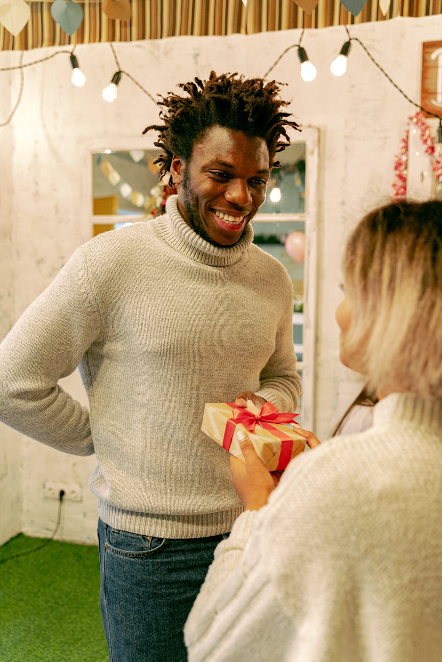 a man in gray knitted jacket receiving a gift