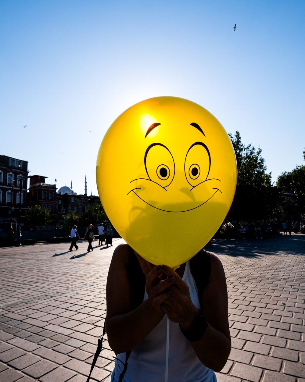 woman holding a yellow balloon with a smiley face in front of her