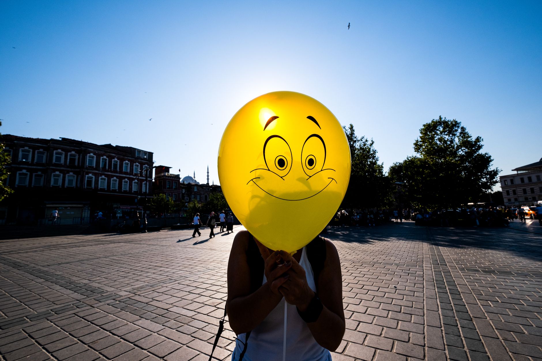 woman holding a yellow balloon with a smiley face in front of her