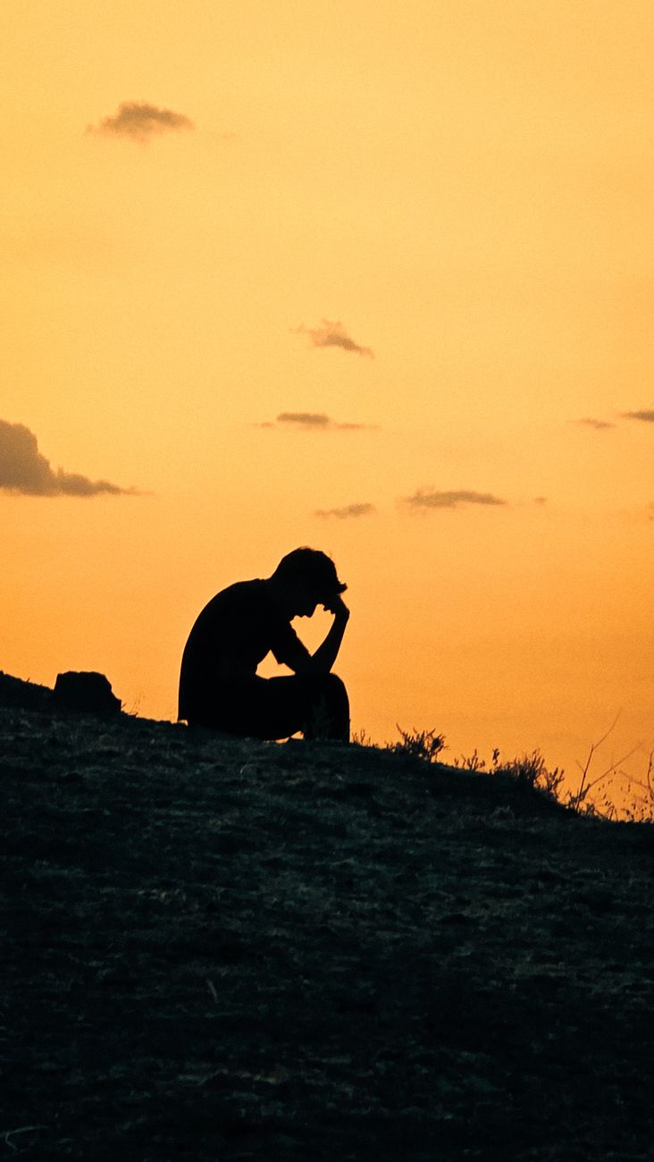 silhouette of person in deep thought at sunset